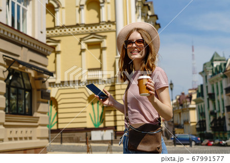 Beautiful Young Woman tourist with takeout coffee in the City Center talking on the phone 67991577