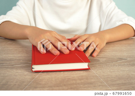 夕暮れ時に本を読む女性。テーブルで本を読む人のクローズアップ 夕暮れ時に本を読む女性。テーブルで本を読む人のクローズアップ 67991650