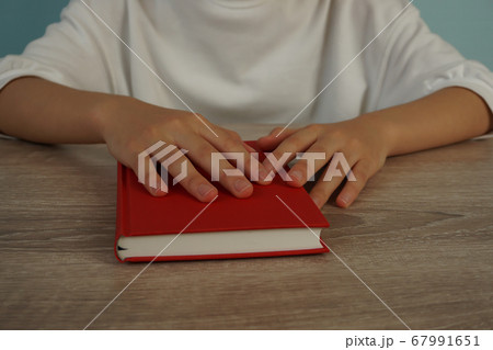 夕暮れ時に本を読む女性。テーブルで本を読む人のクローズアップ 67991651