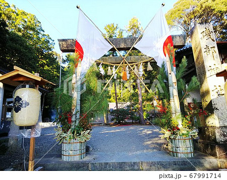 初詣の神社の鳥居の前に日の丸と門松。手前に提灯 67991714