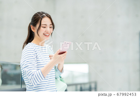 キャンパスでスマホを操作する大学生 キャンパスでスマホを操作する大学生 67992453