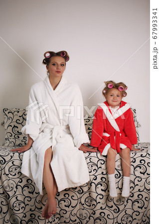 Photo of mother and daughter in white coats. They are sitting on the couch Photo of mother and daughter in white coats. They are sitting on the couch 67993341
