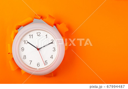clock showing up from torn orange paper 67994487