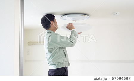 天井にシーリングライトを取り付ける作業員 67994697