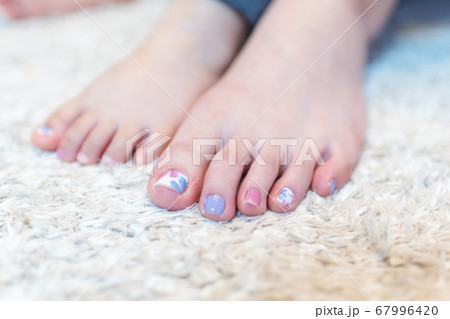 若い女性と女の子の足を並べる 爪にネイルシールを貼るの写真素材