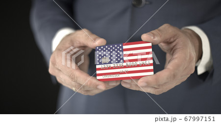 Businessman holding plastic bank card with printed flag of the United States, fictional numbers 67997151