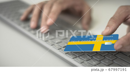 Man pays online with plastic bank card with printed flag of Sweden. Fictional numbers Man pays online with plastic bank card with printed flag of Sweden. Fictional numbers 67997191