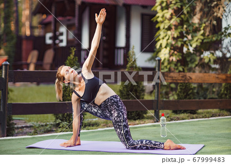 Woman practicing morning yoga and stretching at backyard. Healthy lifestyle 67999483