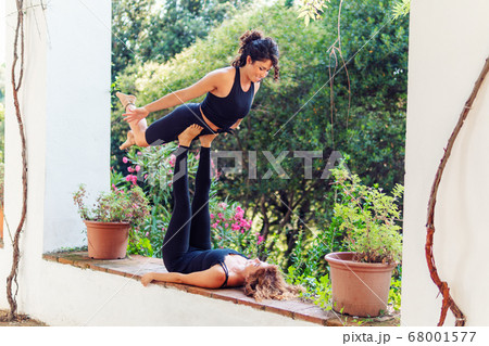 Two beautiful women doing acroyoga in the garden or park Two beautiful women doing acroyoga in the garden or park 68001577