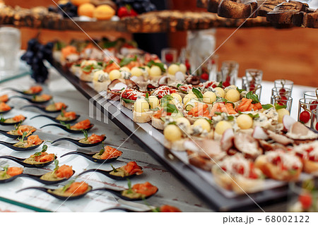 Different light snack on glass and wooden tray 68002122