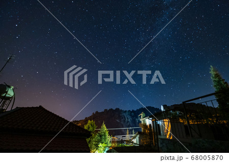 Stars and Milky Way over the forest and a house at 68005870