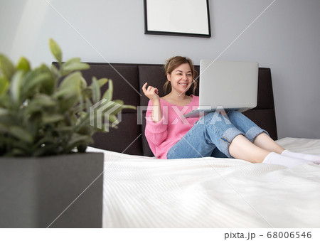 A beautiful girl is sitting in pink sweater with a laptop , chatting. A beautiful girl is sitting in pink sweater with a laptop , chatting. 68006546