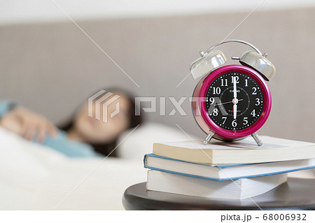 睡眠中の女性のそばに置かれた目覚まし時計 睡眠中の女性のそばに置かれた目覚まし時計 68006932