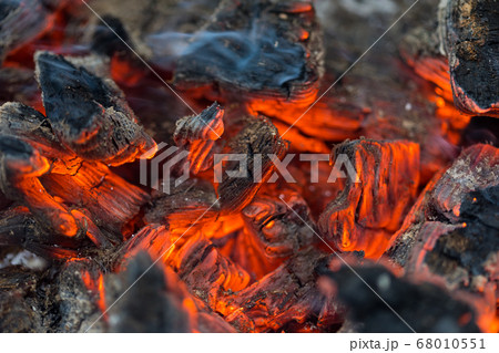 Flame incinerates firewood and transforms it ashes, close up, shallow depth of field. Blaze in a large stove. Nature texture of fire. The flame of fire burns in the brazier, smoldering firewoods. 68010551