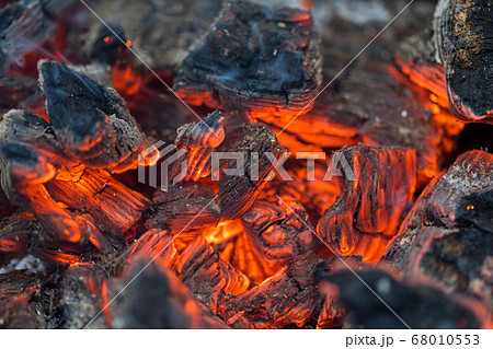 Flame incinerates firewood and transforms it ashes, close up, shallow depth of field. Blaze in a large stove. Nature texture of fire. The flame of fire burns in the brazier, smoldering firewoods. 68010553