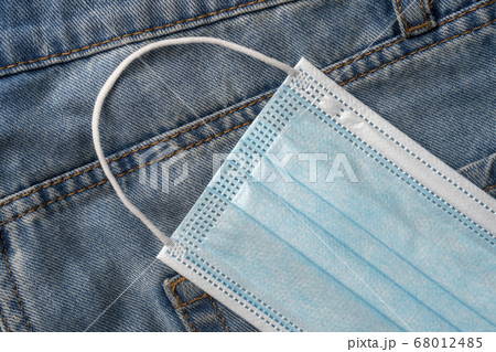 Medical protective surgical mask in a pocket of blue jeans close-up. Coronavirus protection concept 68012485
