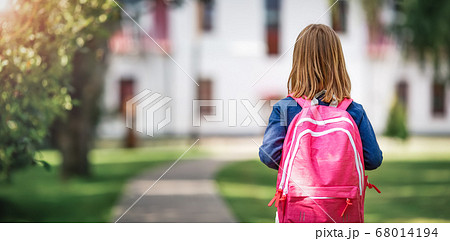 Girl with rucksack infront of a school building 68014194