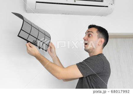 The guy cleans the filter of the home air The guy cleans the filter of the home air 68017992
