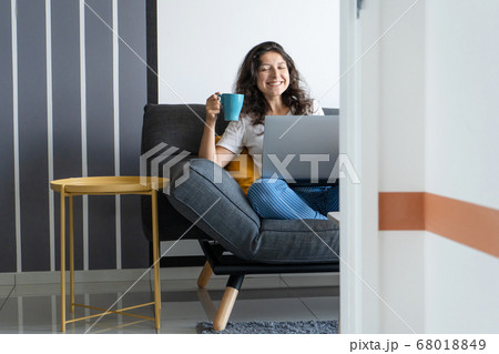 Beautiful girl sitting with a laptop on a sofa in 68018849