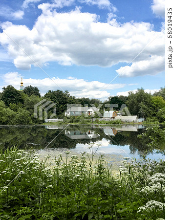 Summer landscape with farm house reflected in lake 68019435