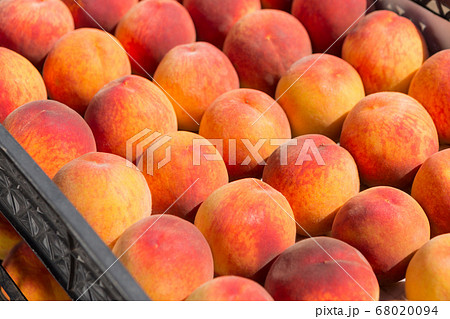a lot of red ripe peaches lie in rows in boxes, a 68020094