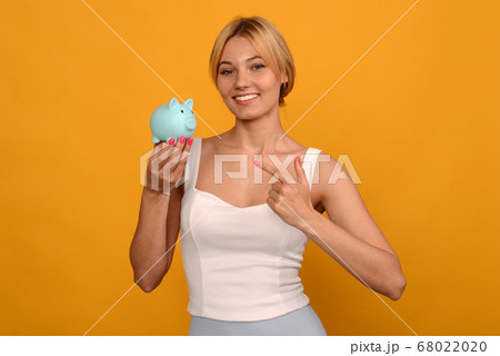Beautiful young girl holding a pig piggy bank and Beautiful young girl holding a pig piggy bank and 68022020