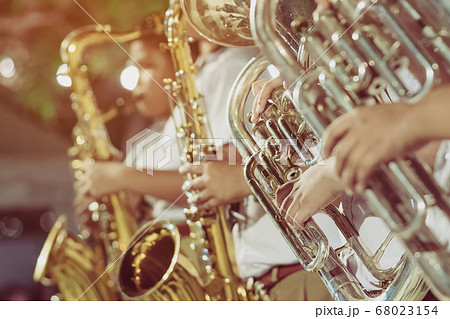 Male student with friends blow the euphonium with the band for performance on stage at night. 68023154