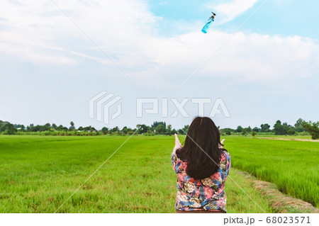 Back view of woman raises her arms to wait for alcohol gel bottle falling from the sky in the rice field.Campaign to prevent the spread of the Corona virus(Covid-19).New normal concept.Selective focus Back view of woman raises her arms to wait for alcohol gel bottle falling from the sky in the rice field.Campaign to prevent the spread of the Corona virus(Covid-19).New normal concept.Selective focus 68023571