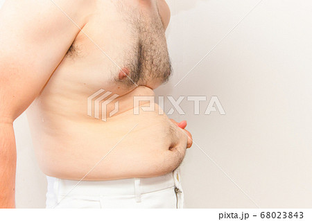 中年太りの男性の上半身 下腹を触る毛深い男性の写真素材
