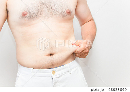 中年太りの男性の上半身 下腹を掴む毛深い男性の写真素材