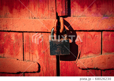 Closed lock on gates made of wooden planks and painted in red, retro Closed lock on gates made of wooden planks and painted in red, retro 68026230