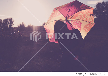 Unrecognizable silhouette of the lady with backlit umbrella Unrecognizable silhouette of the lady with backlit umbrella 68026365