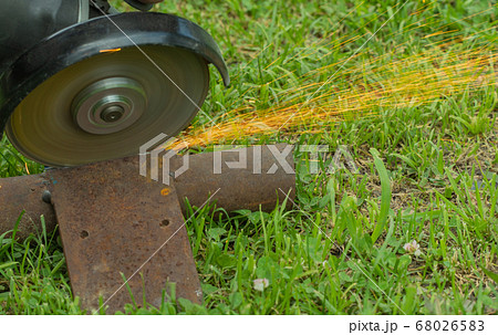 cutting metal on grass with a hand tool. sparks flying from iron. selective focus. 68026583