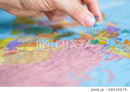 Man pins a new destination on a world map, for his next trip. Travel destination, pin on the map. Very selective focus, blur on all edges and special lightening. 68026674