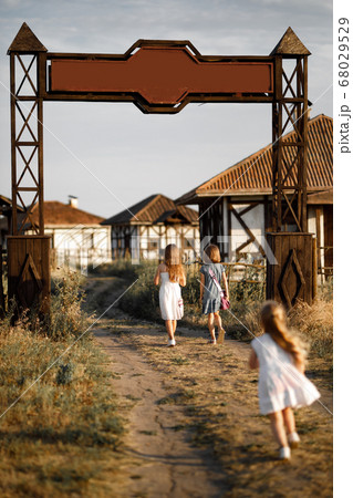 three girl coming out of the gate of the village 68029529