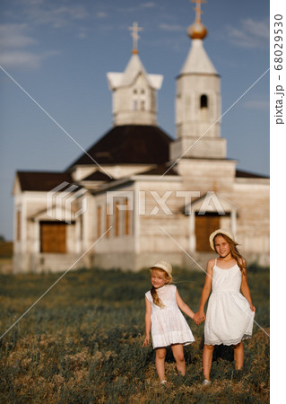 girls hold hands and stand against  wooden Church 68029530