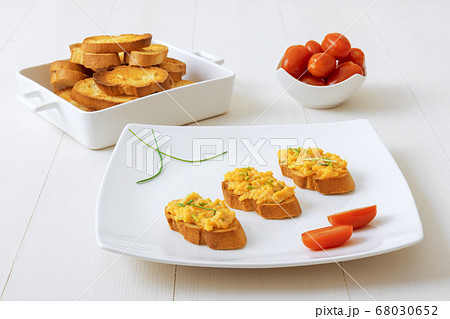 Grilled toasts and scrambled eggs, chive herbs and cherry tomatoes on white table background 68030652