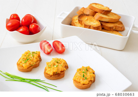 Grilled toasts and scrambled eggs, chive herbs and cherry tomatoes on white table background Grilled toasts and scrambled eggs, chive herbs and cherry tomatoes on white table background 68030663