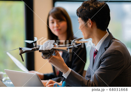 ドローン ビジネス スーツ オフィス  男女  2人 正面 飛行中 商談 挨拶 空撮 午前 明るい  68031668