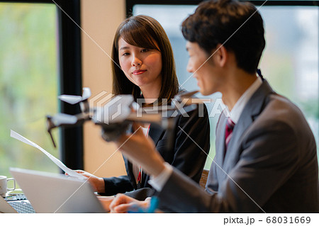 ドローン ビジネス スーツ オフィス  男女  2人 正面 飛行中 商談 挨拶 空撮 午前 明るい  68031669