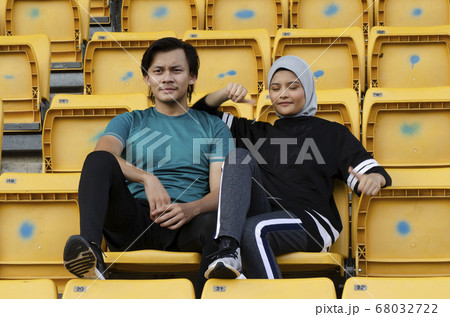 young couple sit in stadium with happy face expression young couple sit in stadium with happy face expression 68032722