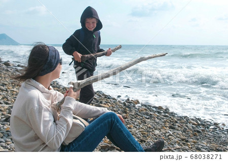 Mom and son play together on the beach. Shoot from branches as from the weapon. 68038271