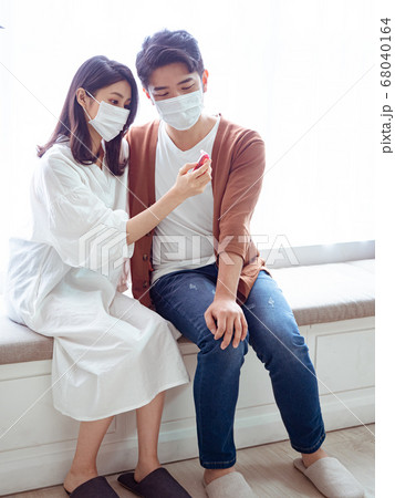 Young asian couple wearing surgical mask and using 68040164