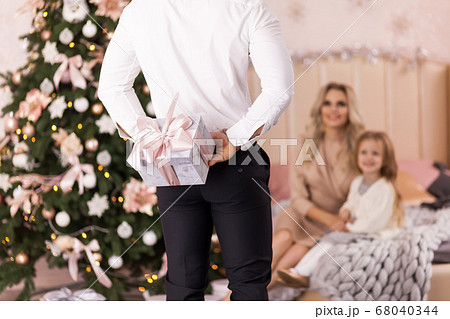 Man hiding gift for family having fun near 68040344