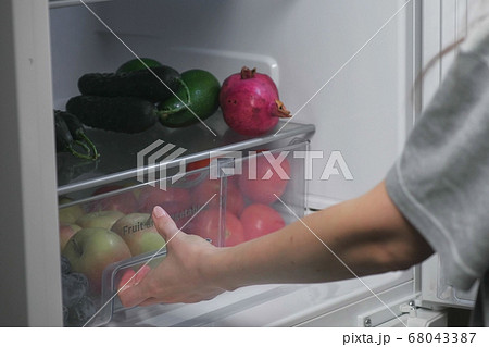 Woman takes out of the fridge food at night. Close-up hands. Woman takes out of the fridge food at night. Close-up hands. 68043387