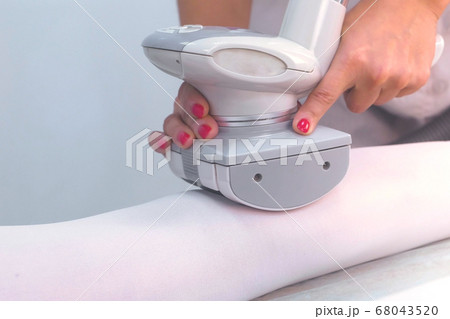 Beautician makes a woman in nylon suit lpg massage on the leg. Leg and hands close-up. 68043520