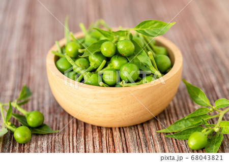 Green circle chilli or cherry peppers in wood bowl 68043821
