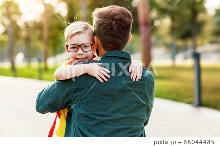 Happy son hugging father before school. Happy son hugging father before school. 68044485