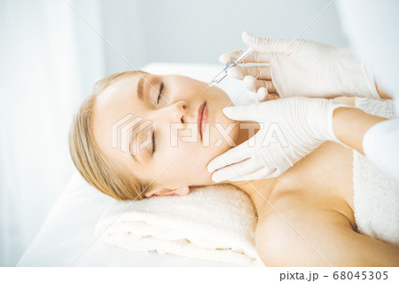 Beautician doctor doing beauty procedure with syringe to blonde female face. Cosmetic medicine, beauty injections concept 68045305