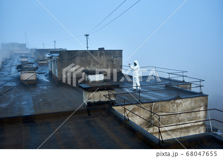 Worker scientist wearing protective coverall and gas mask doing ecological tests on the roof Worker scientist wearing protective coverall and gas mask doing ecological tests on the roof 68047655